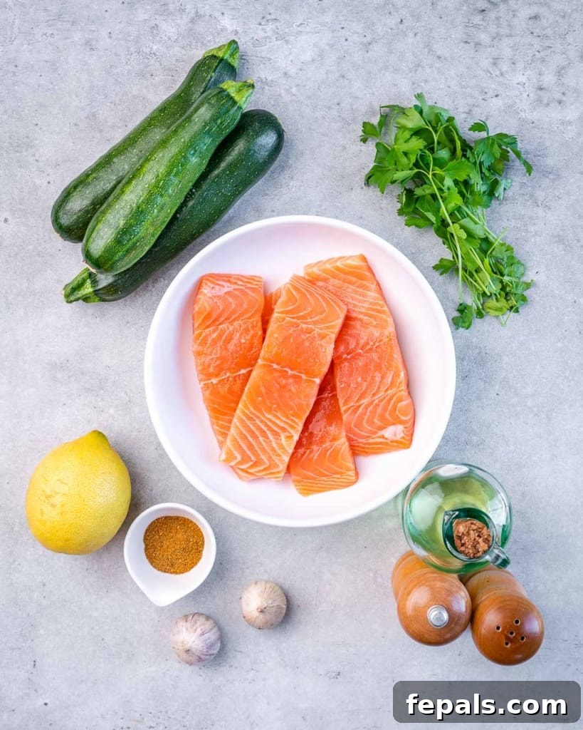 Effortless Cajun Baked Salmon 4 Ingredients laid out on a table to make baked Cajun salmon fillets, including salmon, zucchini, lemon, parsley, garlic, and spices.