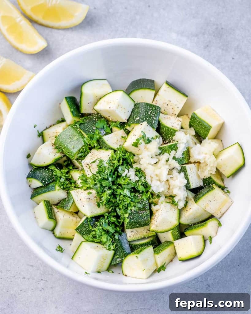 Effortless Cajun Baked Salmon 7 Chopped raw zucchini on a plate, seasoned with minced garlic and fresh parsley, ready to be added to the pan.