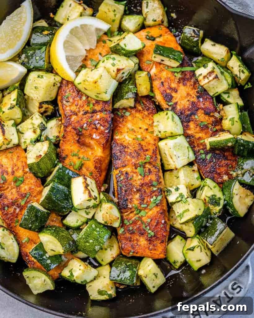 Effortless Cajun Baked Salmon 9 Top view of baked salmon fillets with chopped zucchini on a black skillet, perfectly cooked and ready to serve.