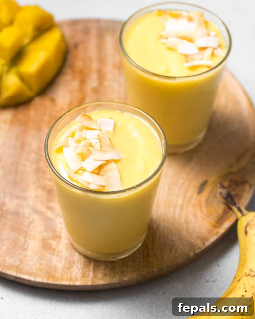 Tropical Mango Delight 2 Side shot of mango smoothie in a cup topped with toasted coconut.