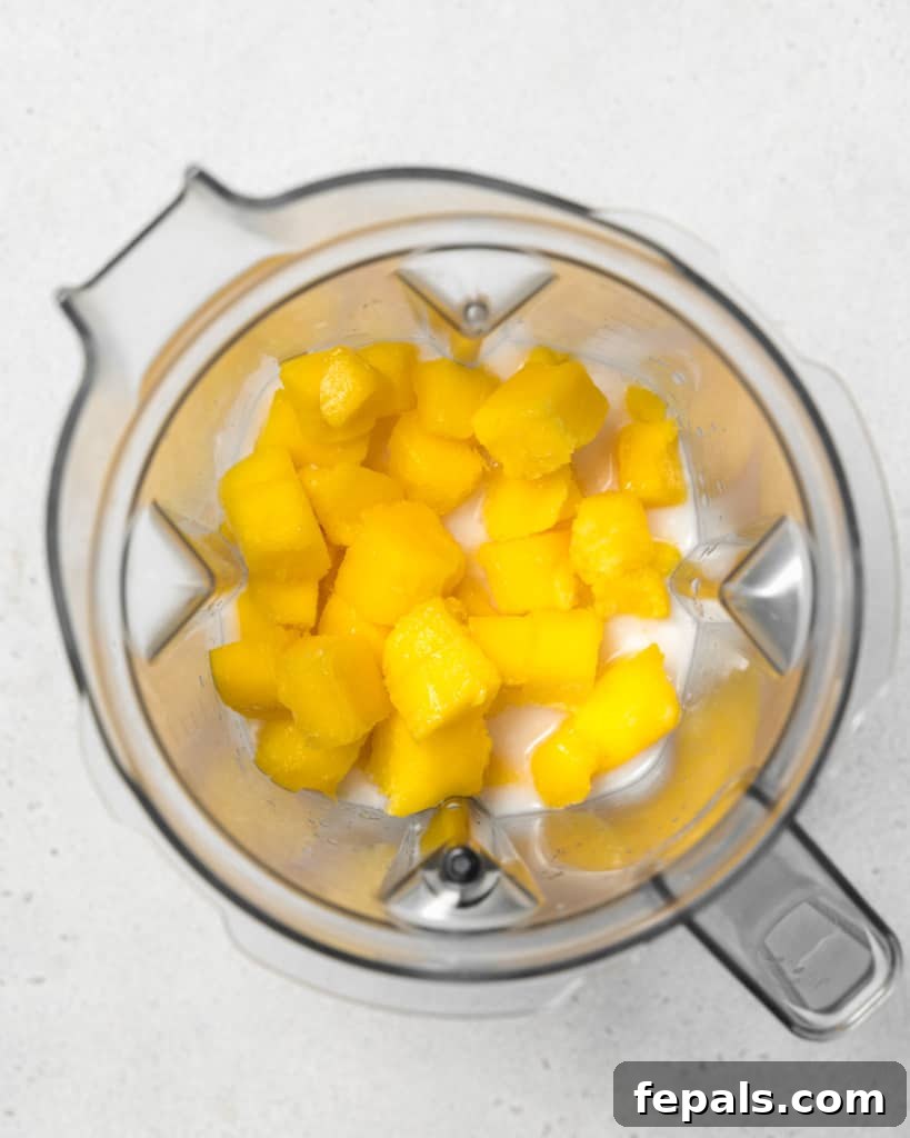 Tropical Mango Delight 6 Adding chunks of mango into a blender.