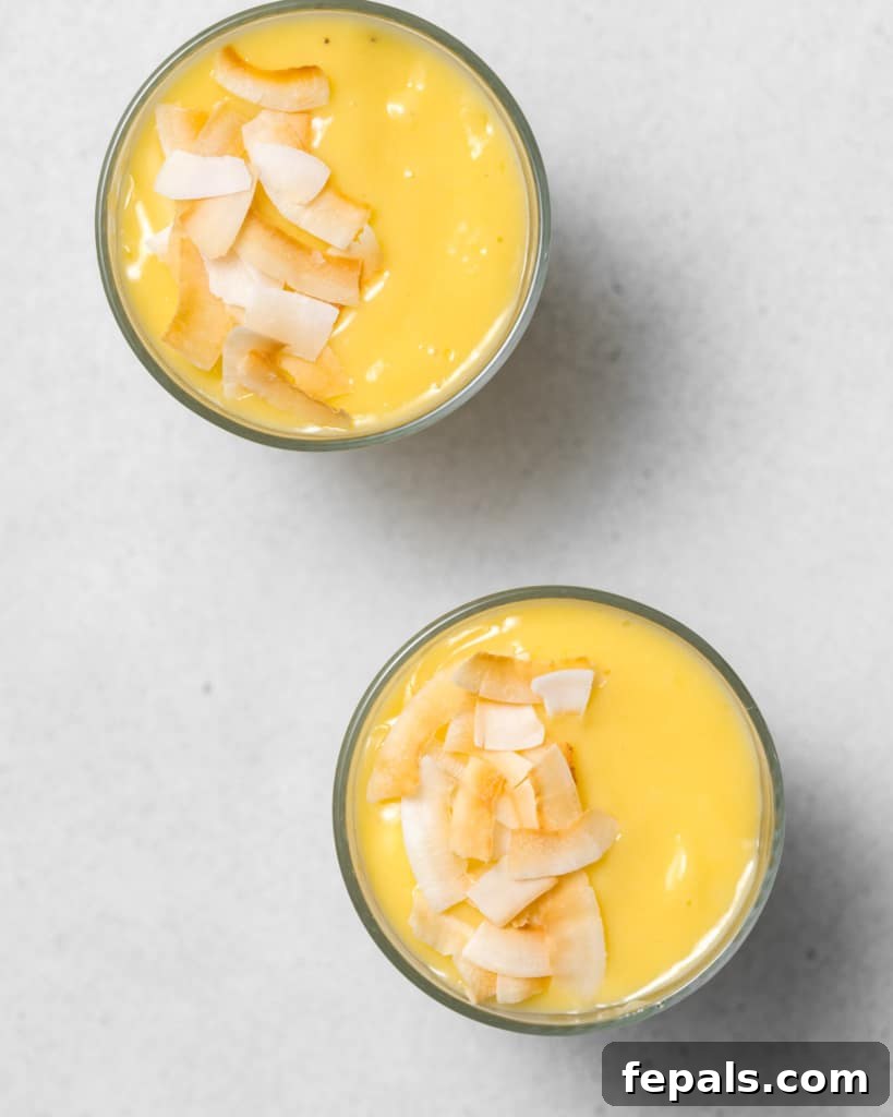 Tropical Mango Delight 9 Two mango smoothies in glasses, topped with coconut flakes.