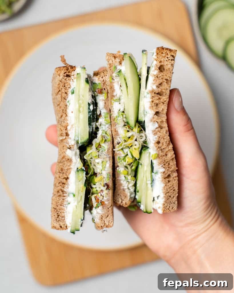 Elegant Cucumber Delights 13 hand holding sandwich middle side up over a plate