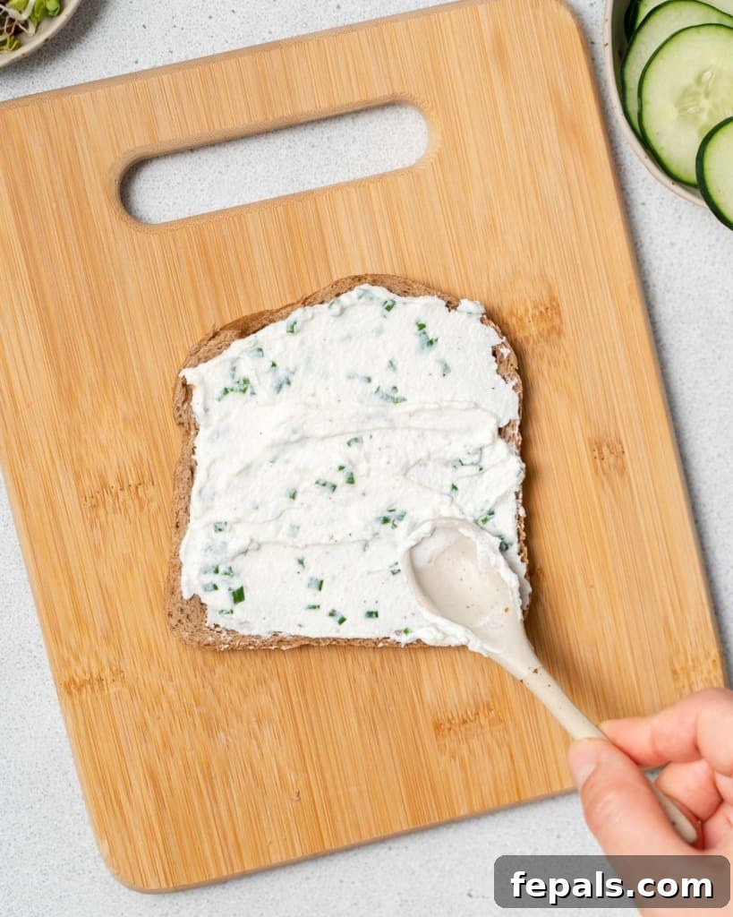 Elegant Cucumber Delights 7 Spreading cream cheese spread on bread.
