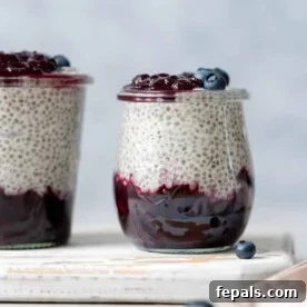 Side shot of a jar with blueberry jam at the bottom of the jar and chia pudding on the top layer topped with more blueberries.