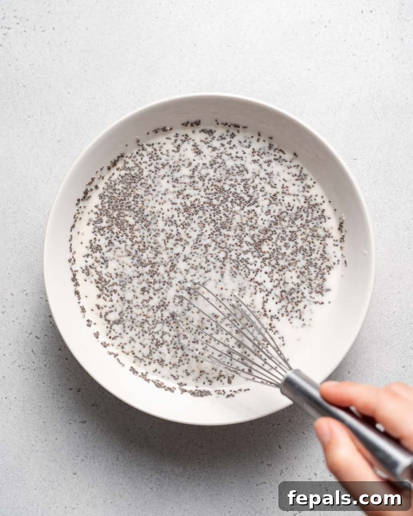 Whisking chia seeds with milk in a bowl, demonstrating the mixing process.
