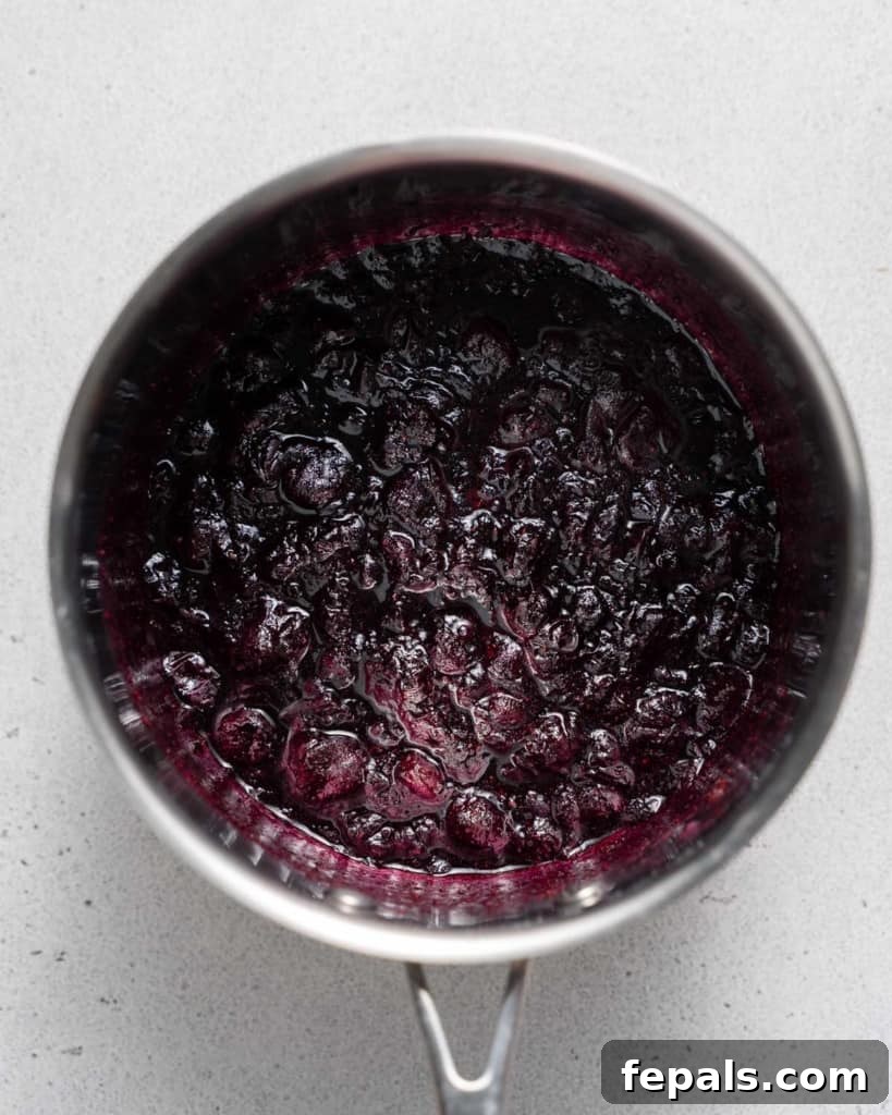 Cooked blueberries in a saucepan, thickened into a sauce after simmering.