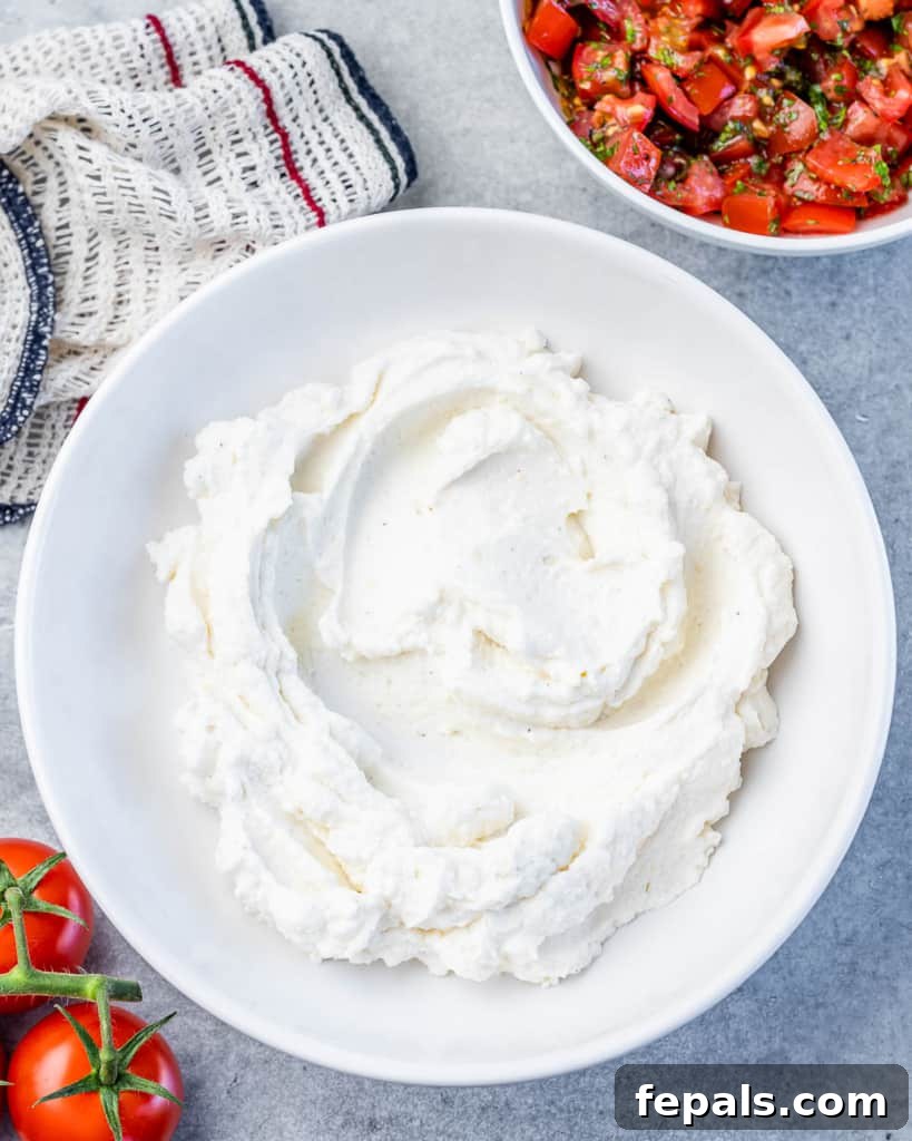 Fluffy Ricotta Dip 6 whipped ricotta cheese spread evenly on a white plate, ready for topping.