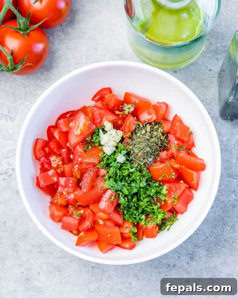 Fluffy Ricotta Dip 7 chopped tomatoes, fresh herbs, and balsamic vinegar being mixed in a bowl for the topping.