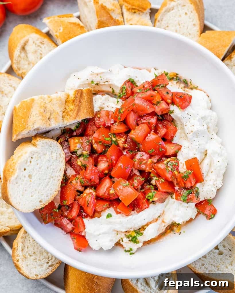 Fluffy Ricotta Dip 8 top view of plated whipped ricotta cheese topped with balsamic tomatoes, served with two slices of crusty baguette on the side.
