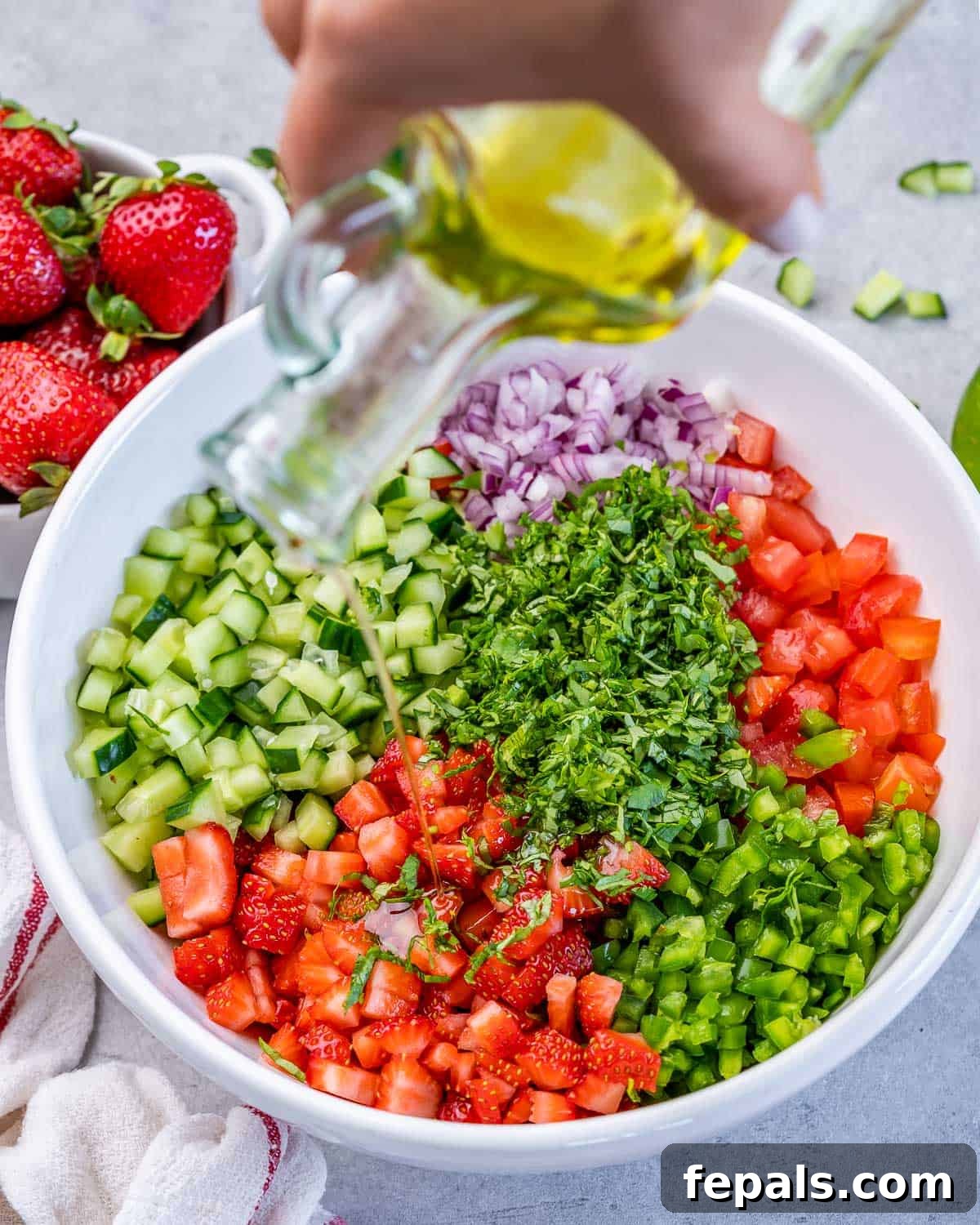 Adding olive oil over strawberry salsa.