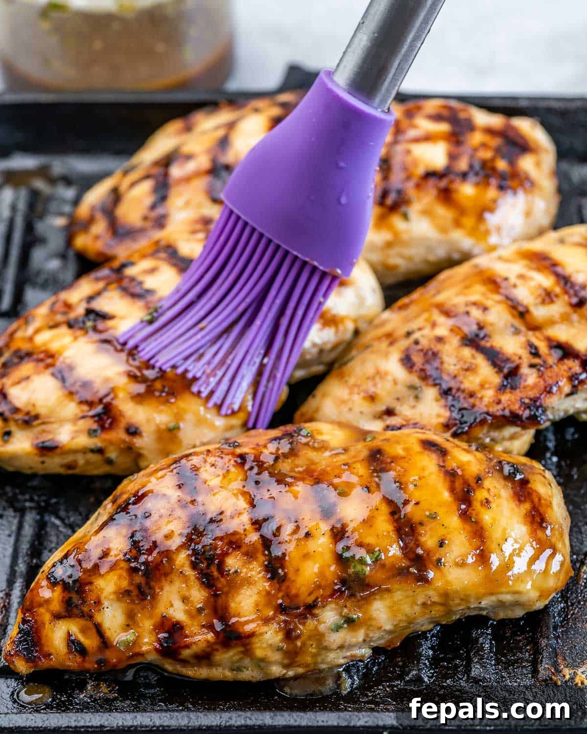 Sweet and Savory Maple Rosemary Chicken 7 Basting grilled chicken breasts on a grill pan with rosemary maple marinade.