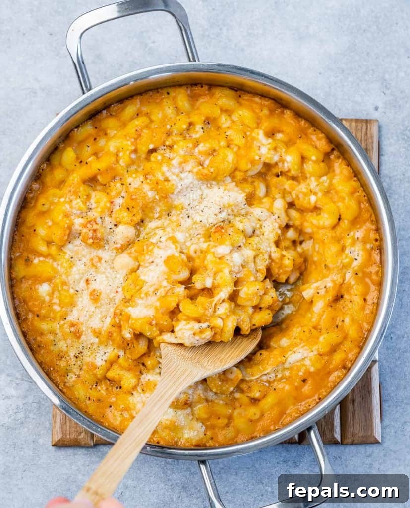 Roasted Pumpkin Mac and Cheese 2 Top view wooden spoon in pumpkin mac and cheese in pan.