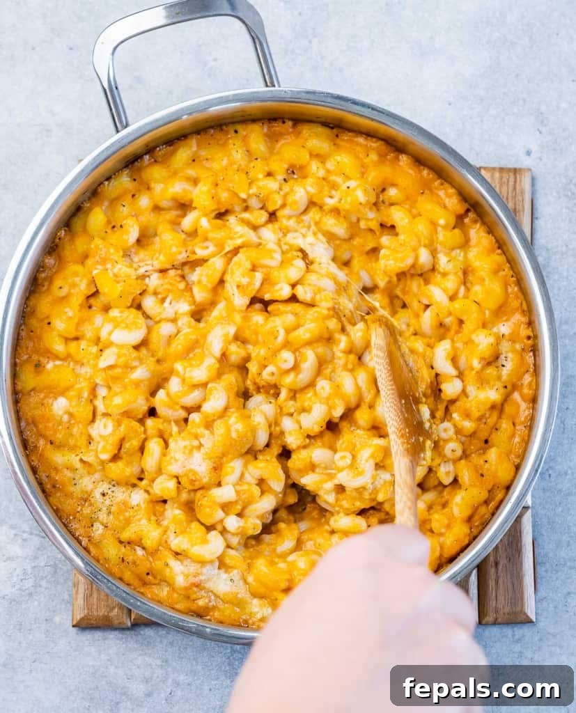Roasted Pumpkin Mac and Cheese 8 Stirring pasta with cheese sauce.