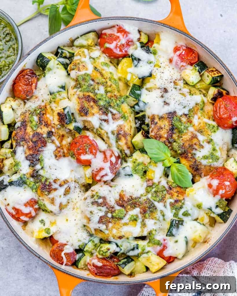Pesto Perfection Chicken 2 top view orange skillet with baked pesto chicken topped with cheese annd fresh tomatoes