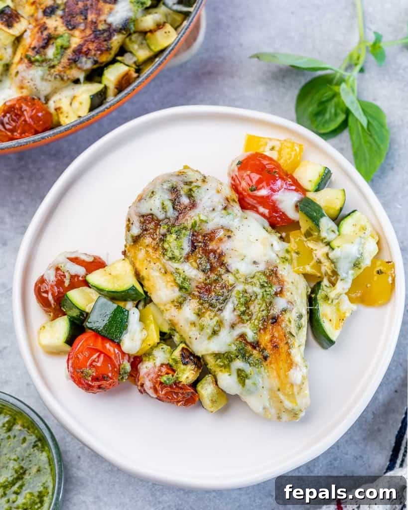 Pesto Perfection Chicken 9 a single baked pesto chicken breast in a round white plate with zucchini and tomatoes