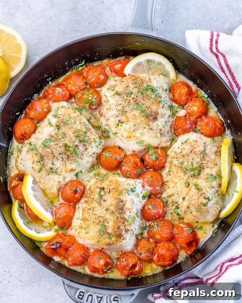 Bright Lemon Garlic Cod Bake 3 top view of a black skillet with baked lemon cods along with cherry tomatoes cod