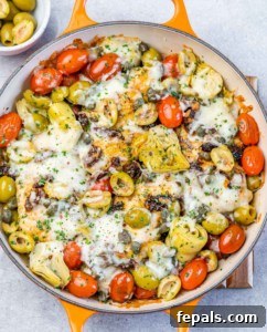 Melted cheese over chicken in a skillet with vegetables.
