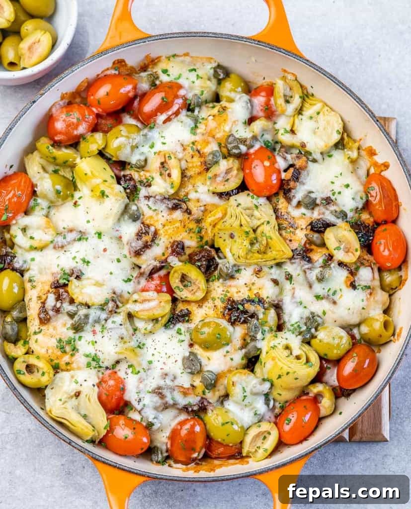 Baked Italian chicken in a skillet, showcasing melted, bubbly mozzarella cheese over the chicken and vegetables.