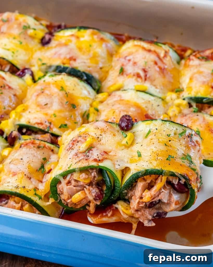 side shot of chicken enchilada roll-ups in a  dish with tomato sauce at bottom