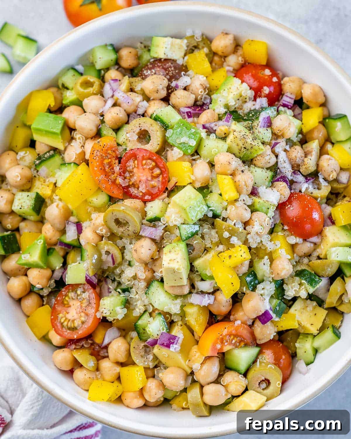 Mediterranean Chickpea Cucumber Quinoa Salad 2 Top view of a vibrant Mediterranean chickpea quinoa salad with avocado in a white salad bowl, ready to be served.