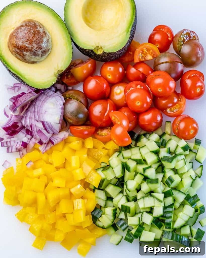 Mediterranean Chickpea Cucumber Quinoa Salad 6 A vibrant mix of freshly chopped cucumber, cherry tomatoes, bell pepper, and red onion in a bowl, prepared for the salad.