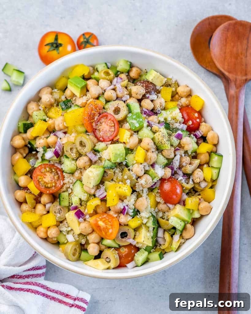 Mediterranean Chickpea Cucumber Quinoa Salad 9 Top view of a round white bowl showcasing a vibrant quinoa and avocado salad, generously topped with chickpeas, olives, and cherry tomatoes.