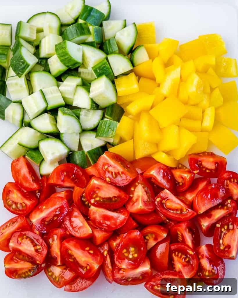 chopped cucumber, bell pepper, and tomatoes on a cutting board