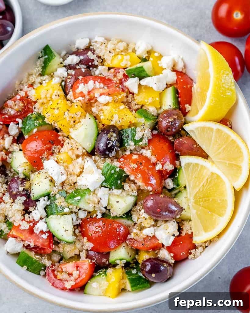 top view of a bowl of quinoa salad topped with crumbled feta cheese and lemon slices to granish