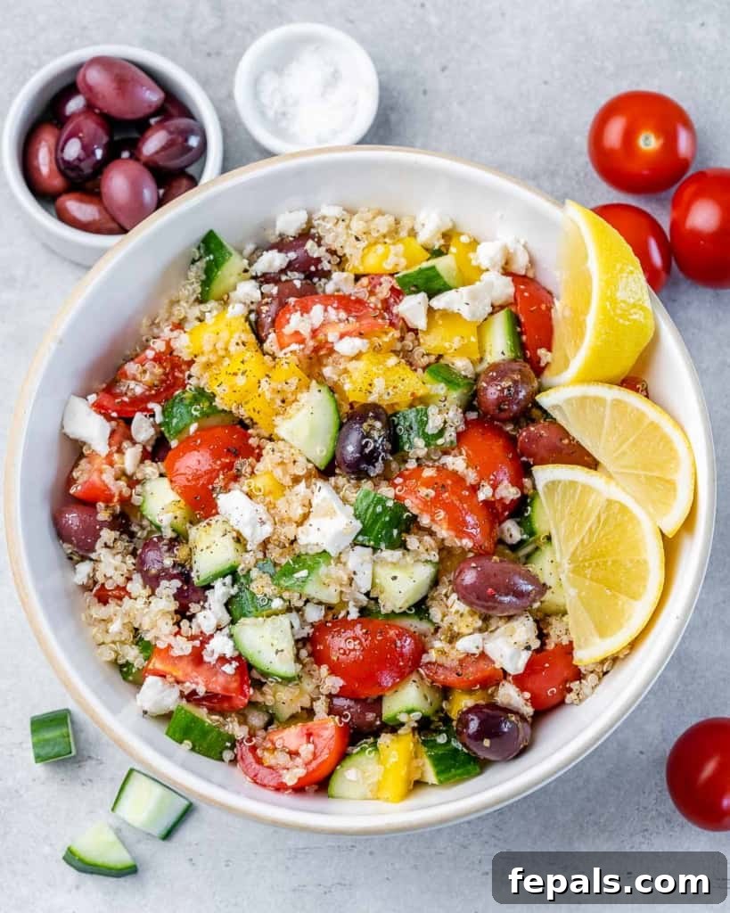 top view bowl of salad made with quinoa, veggies, olives, and crumbled feta cheese. on the top left corner is a small bowl of black olives next to the salad bowl