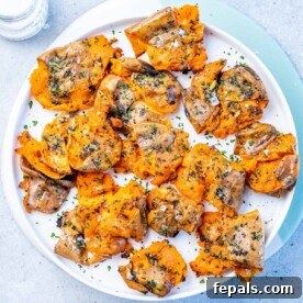 Top view baked smashed sweet potatoes on a round white plate.