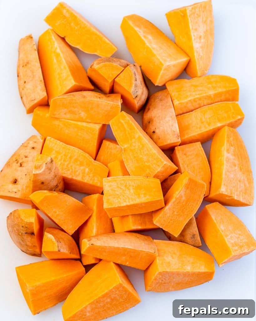Golden Roasted Sweet Potato Smash 5 Close-up of perfectly chopped and peeled sweet potatoes arranged on a baking sheet, ready for the initial bake.