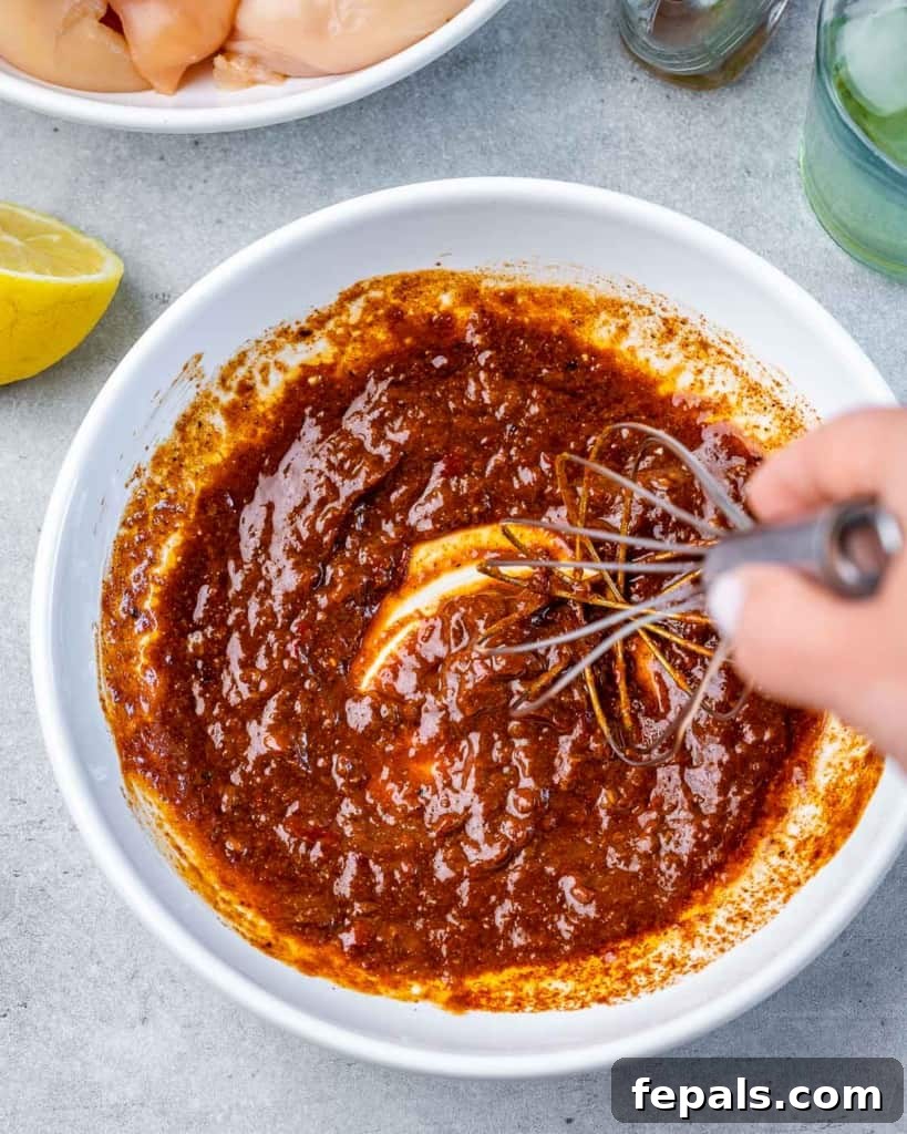Spicy Harissa Roasted Chicken 6 hand holding a whisk and mixing seasonings on a plate