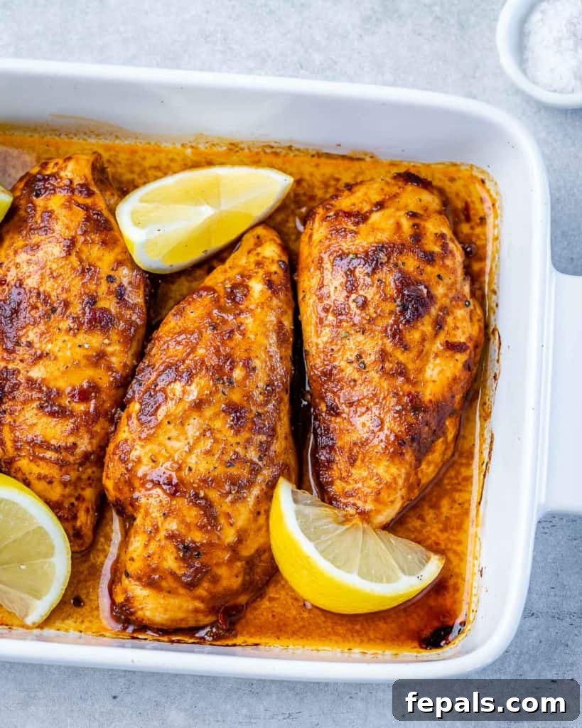 Spicy Harissa Roasted Chicken 9 top view of a white baking dish with 3 chicken breasts baked with lemon slices