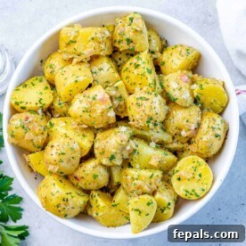 Hearty Warm German Potato Salad 11 Top view of herbed potato pieces on a white round bowl.