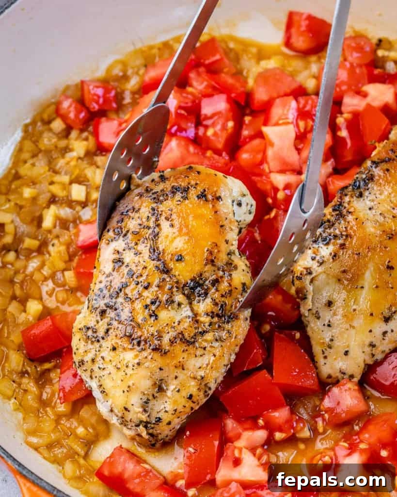 Tuscan Chicken Pomodoro 7 Using tongs to place cooked chicken into a pan with tomatoes.