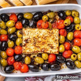 top view of white dish with baked feta cheese block and a mix of tomato and olives