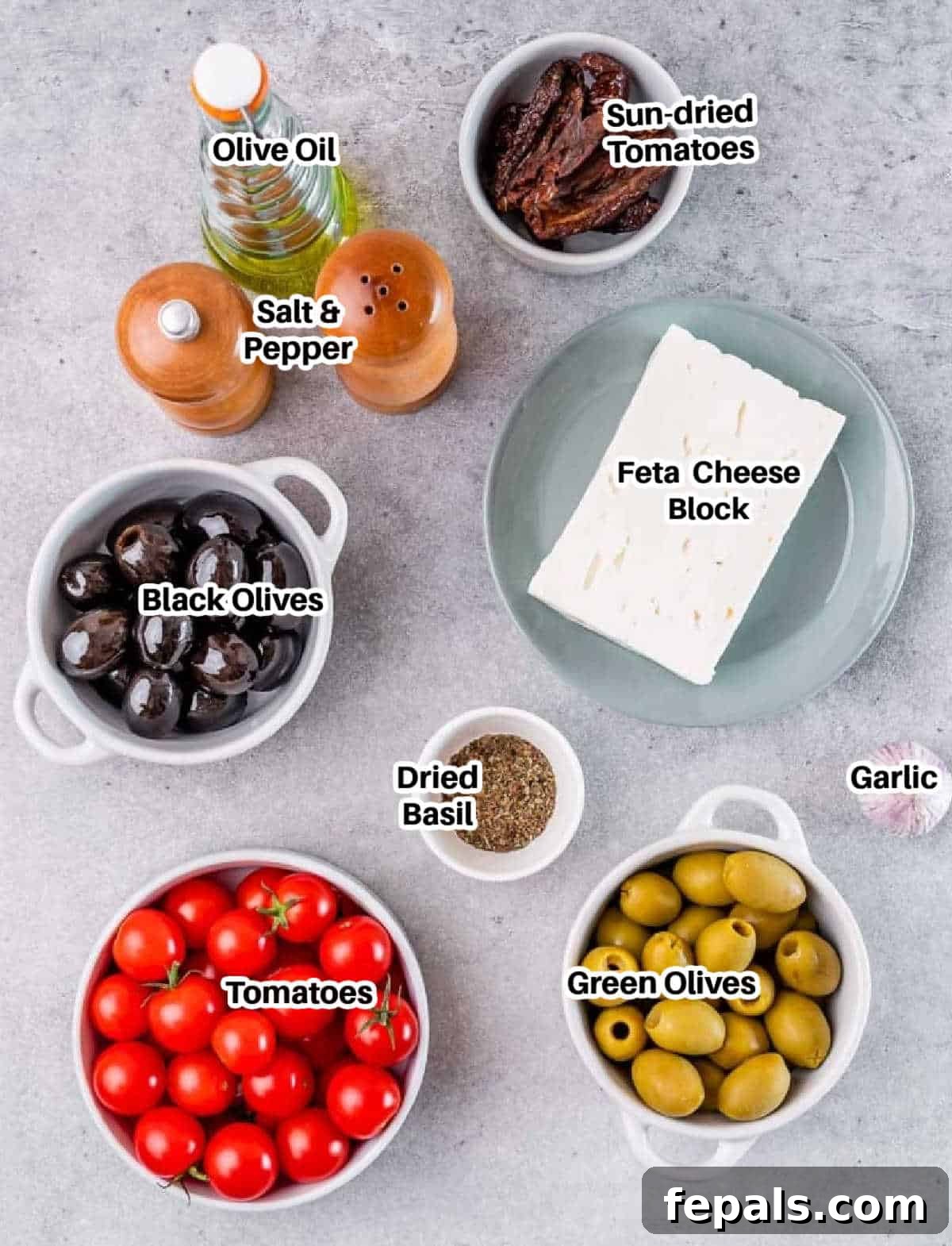 ingredients to make baked feta dip, including feta, olives, tomatoes, and herbs