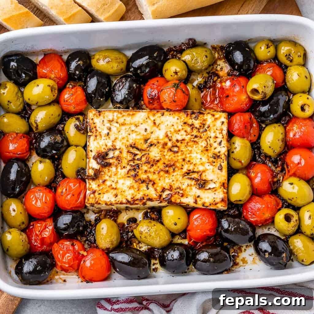 top view of white dish with baked feta cheese block and a mix of tomato and olives, beautifully presented