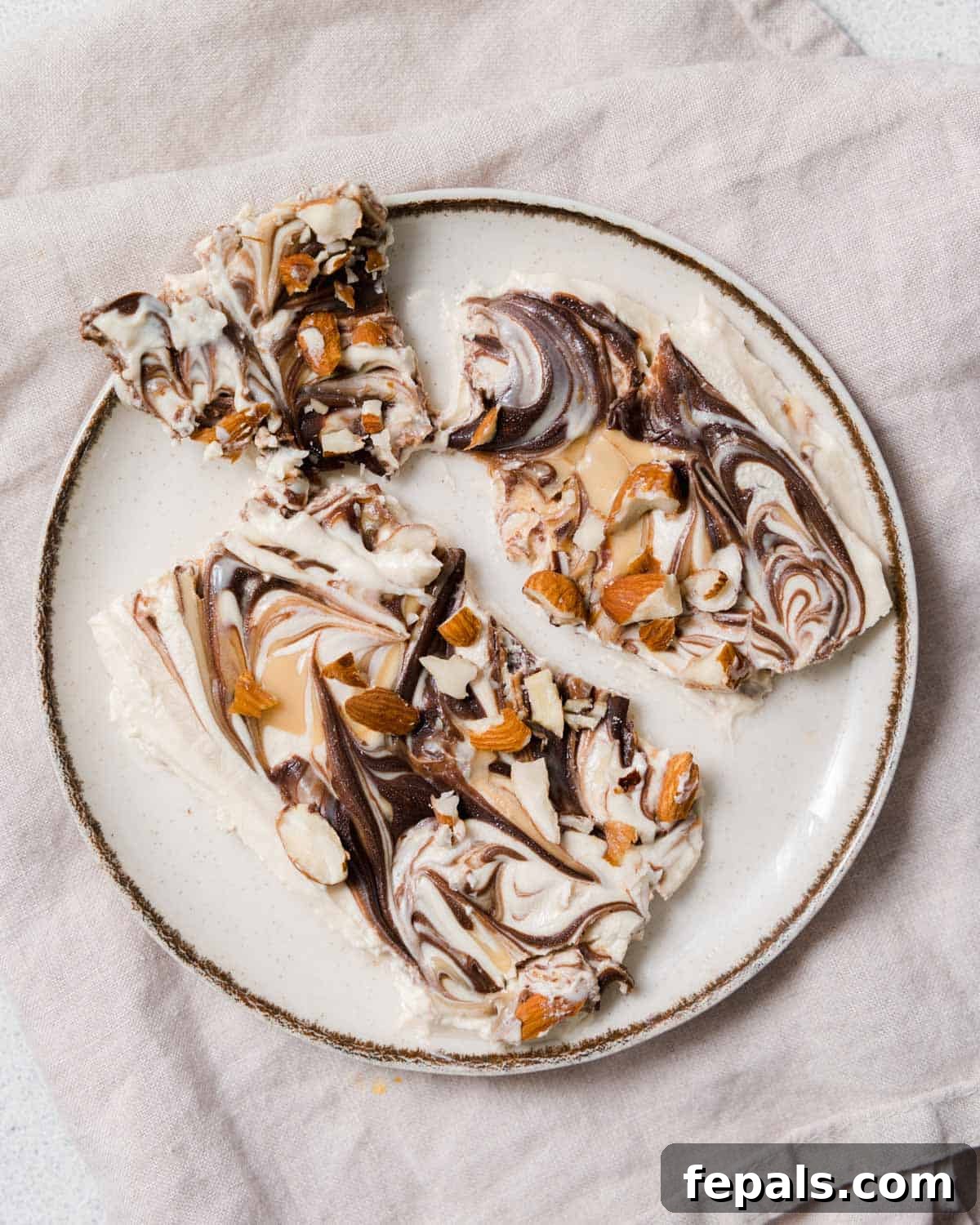 Peanut Butter Yogurt Frosty Bark 2 Top view of frozen yogurt bark on a plate, showcasing its appealing layers and toppings.