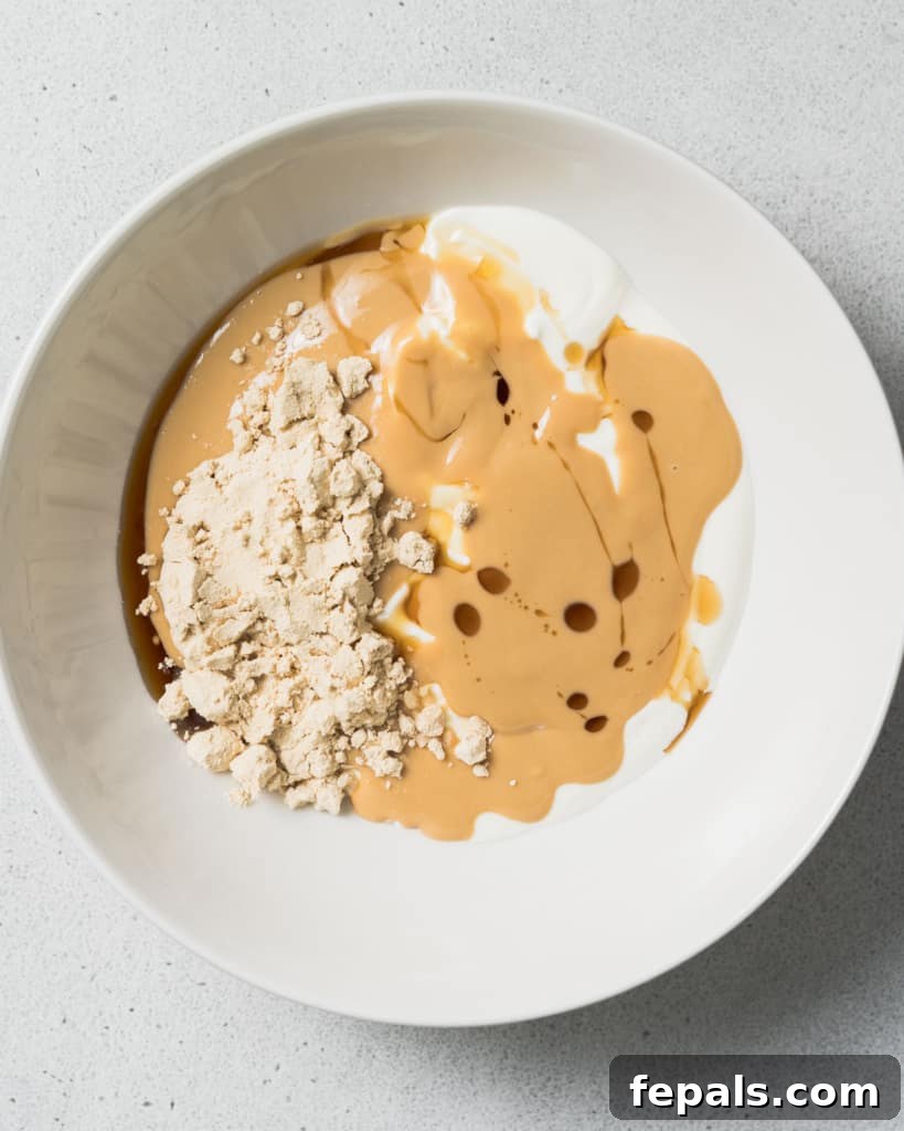 Peanut Butter Yogurt Frosty Bark 5 Yogurt, peanut butter and maple syrup in a bowl, ready to be mixed.
