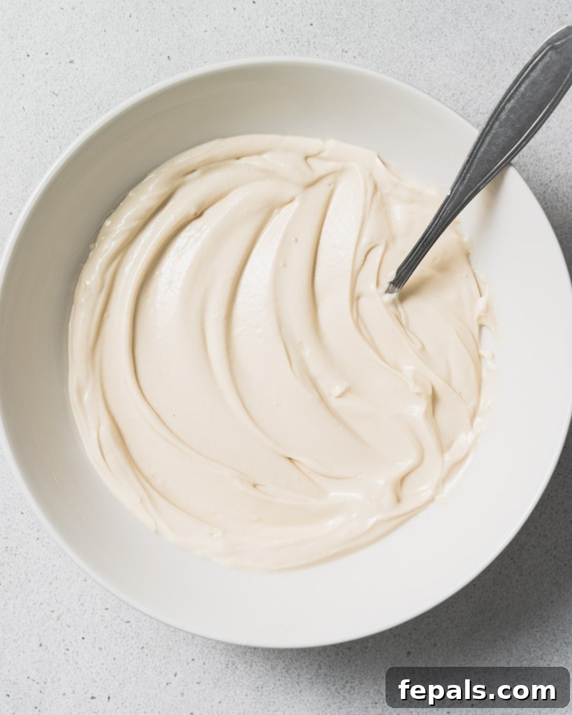 Peanut Butter Yogurt Frosty Bark 7 A spoon resting in a bowl filled with the creamy yogurt mixture, indicating it's well-combined.