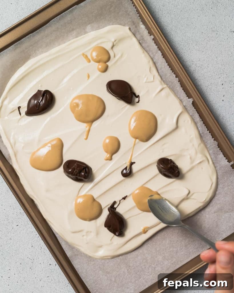 Peanut Butter Yogurt Frosty Bark 9 A spoonful of peanut butter and melted chocolate being added to the yogurt layer.