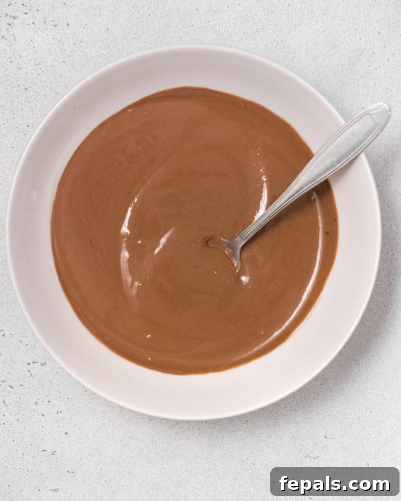 Chocolate dip being stirred together in a bowl, showing the smooth, consistent texture developing.