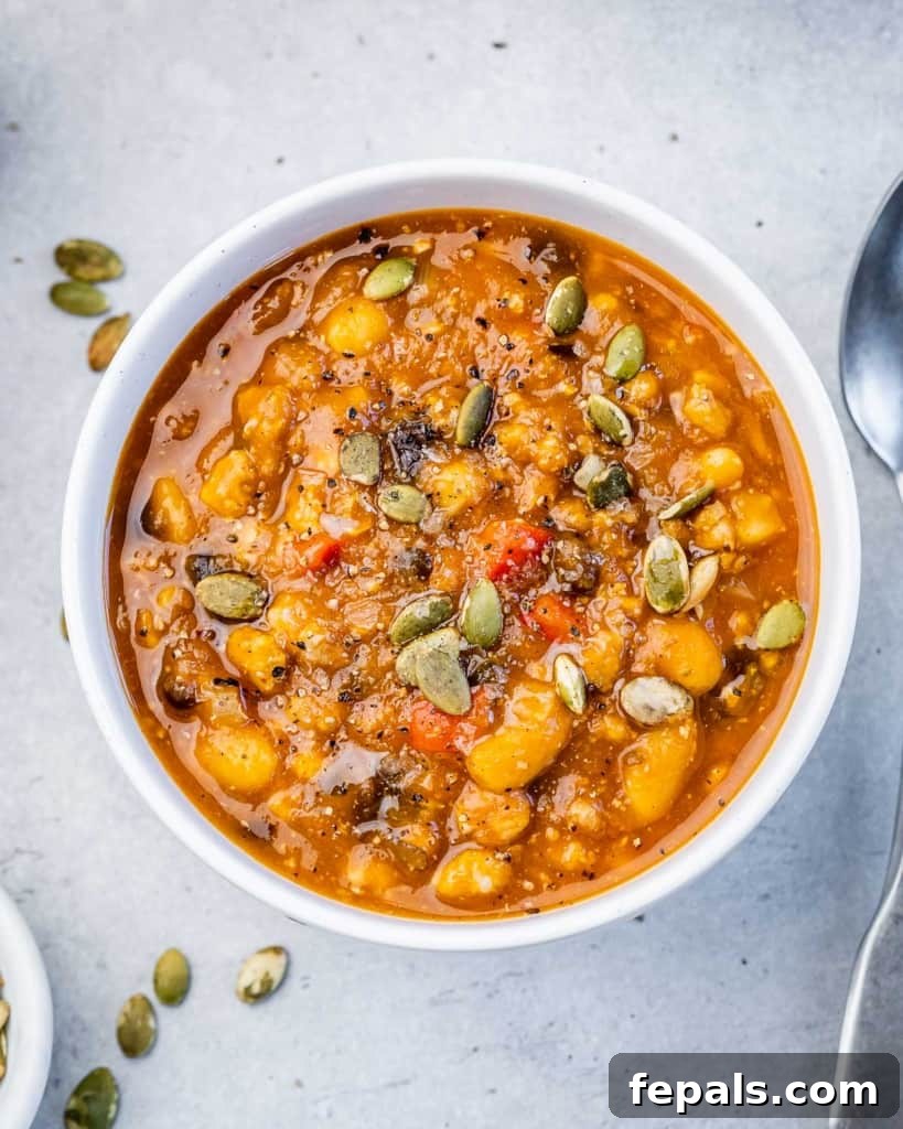 A close-up of Turkey Pumpkin Chili served in a white bowl, generously topped with toasted pumpkin seeds for an extra crunch.