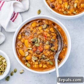 Orange-looking chili in a round white bowl with a spoon in the bowl.