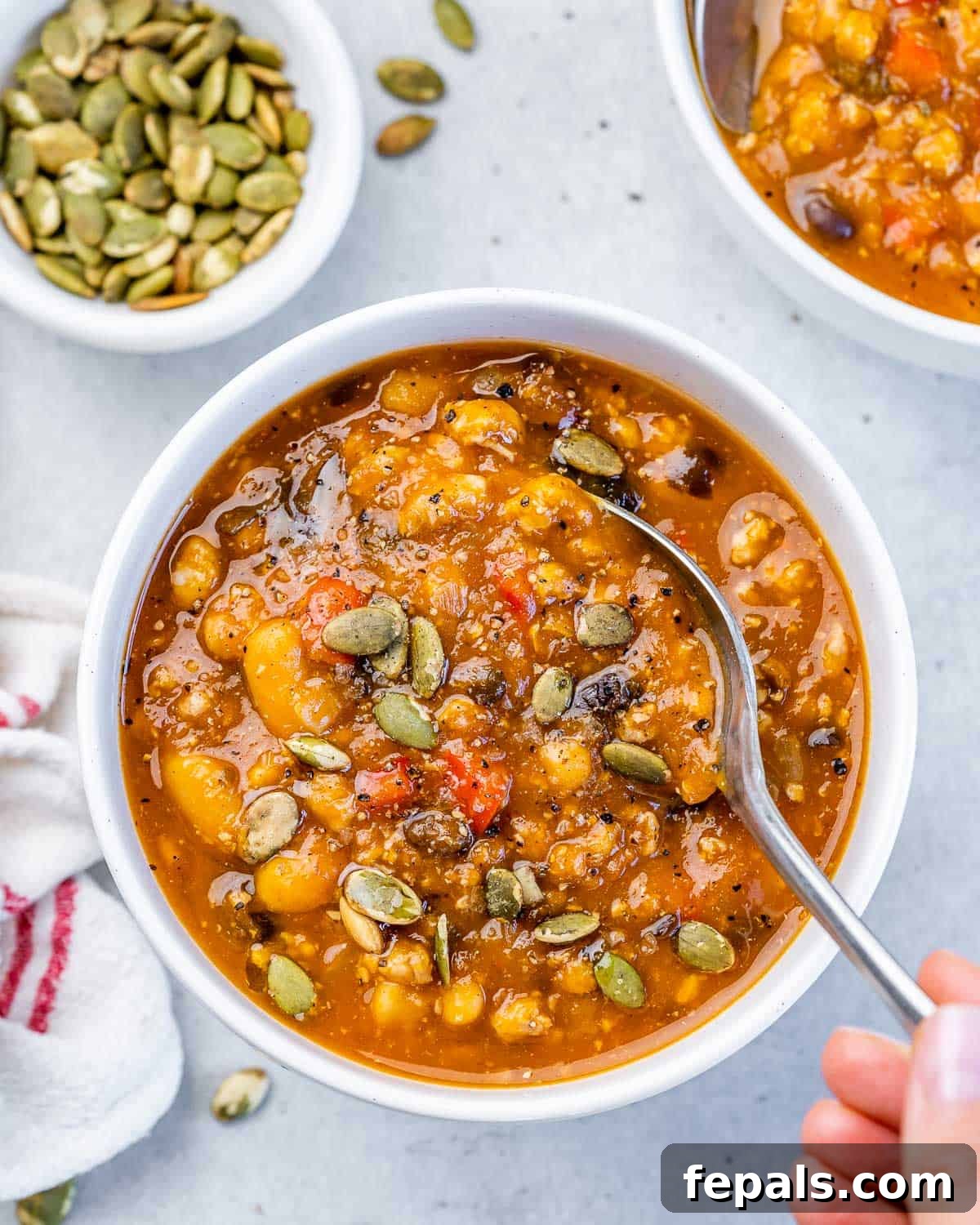 A close-up of a spoon stirring creamy Turkey Pumpkin Chili in a pot, highlighting the rich texture and warm colors.