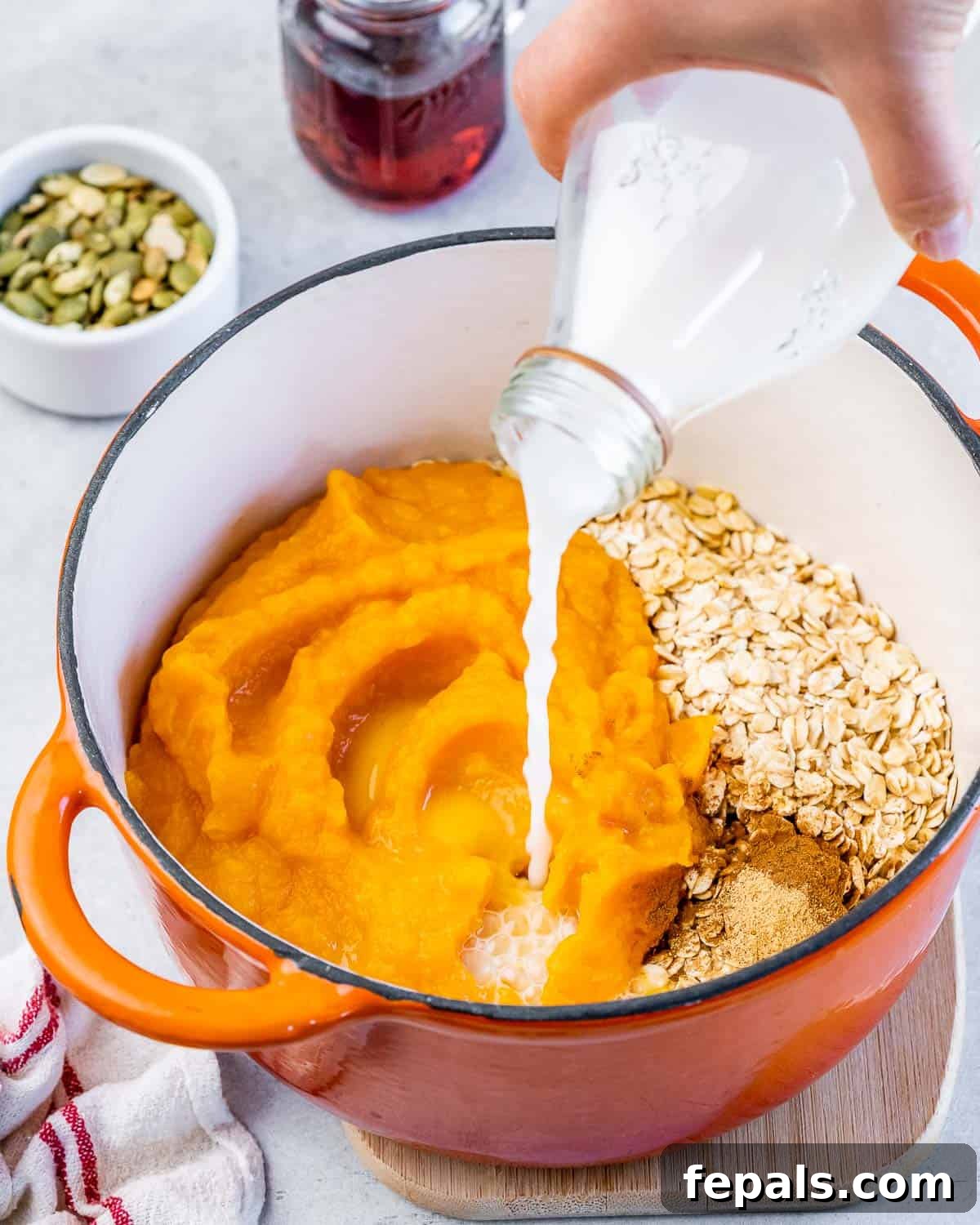 Pouring water into pot with pumpkin and oats.