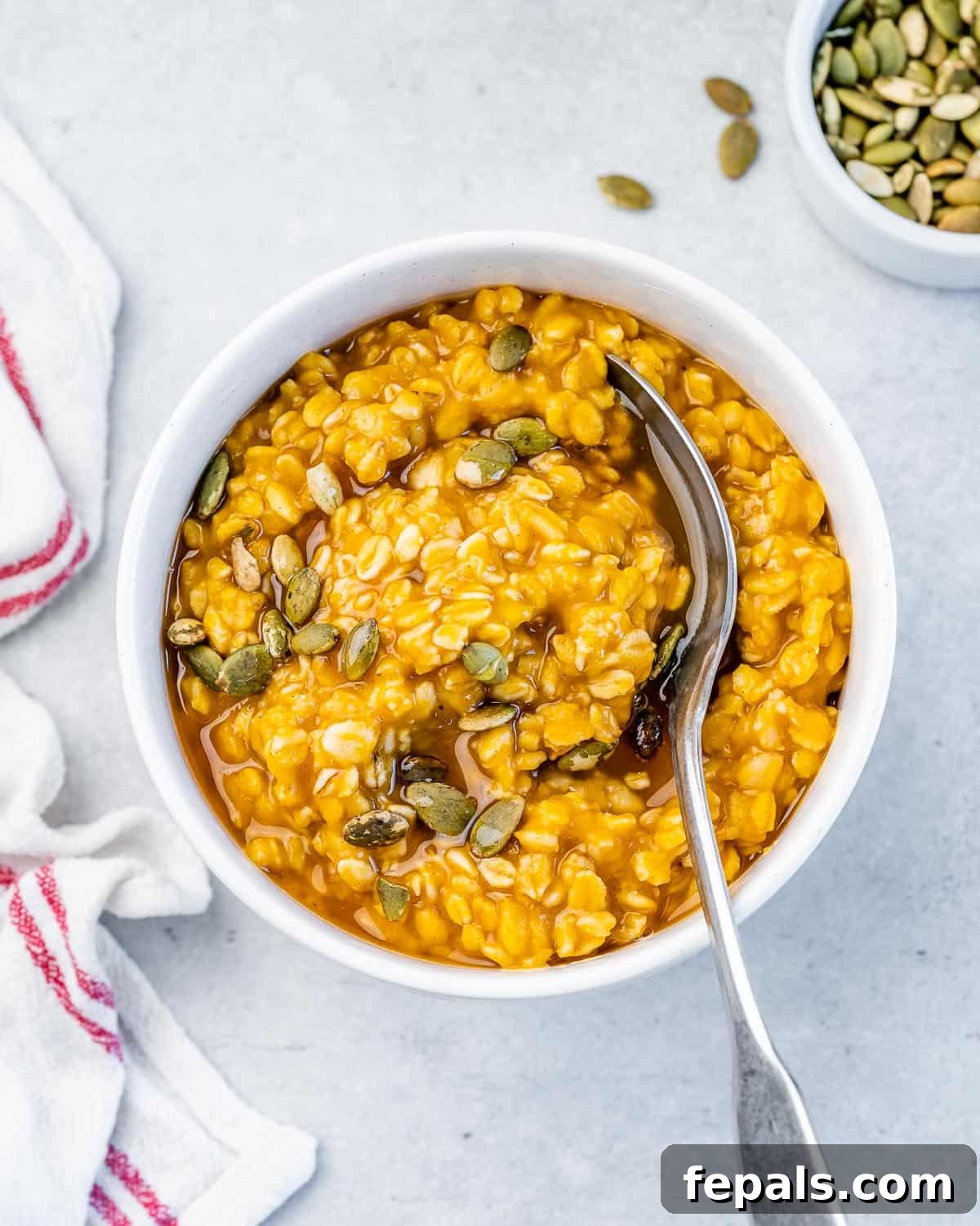 Stirring pumpkin oatmeal in a bowl using a spoon.