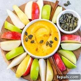 White bowl with pumpkin pie fruit dip surrounded by apple slices.